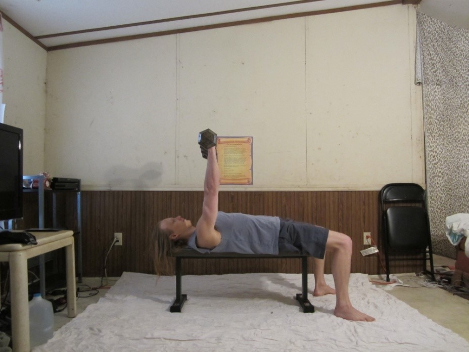 Dumbbell bench press picture demonstrating the middle of the repetition from a side viewpoint.