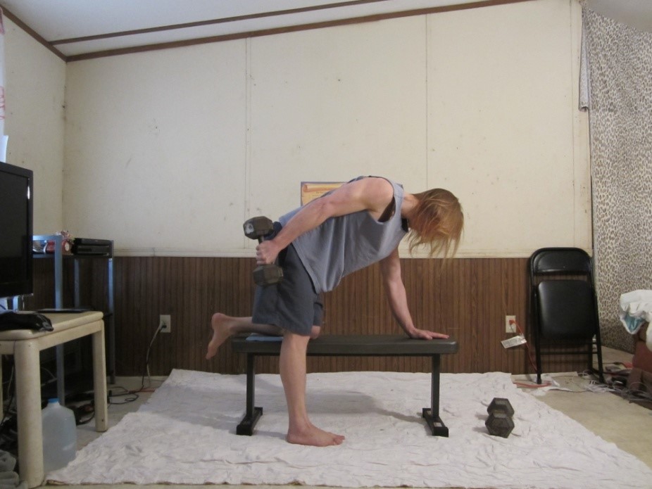 Dumbbell tricep kickback picture demonstrating the middle of the repetition for the right arm from a side viewpoint.