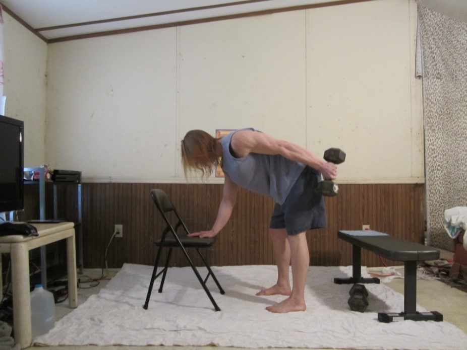 Dumbbell tricep kickback picture demonstrating the middle of the repetition for the left arm from a side viewpoint.